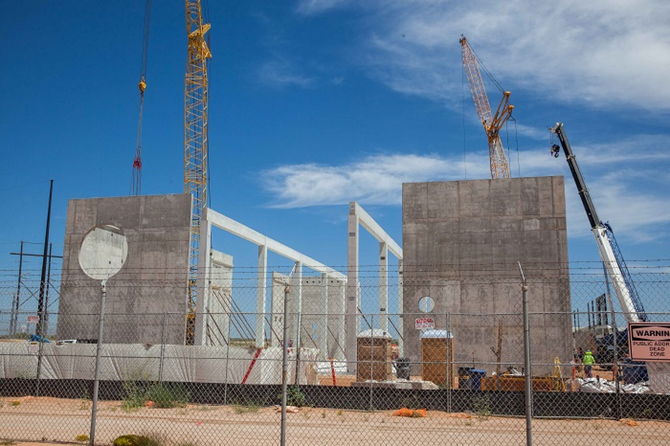 Cranes lifting precast wall sections into place tower over the Waste Isolation Pilot Plant’s (WIPP) Salt Reduction Building (SRB), part of the site’s Safety Significant Confinement Ventilation System. The interior columns will support the next phase of construction: the installation of precast roof panels.