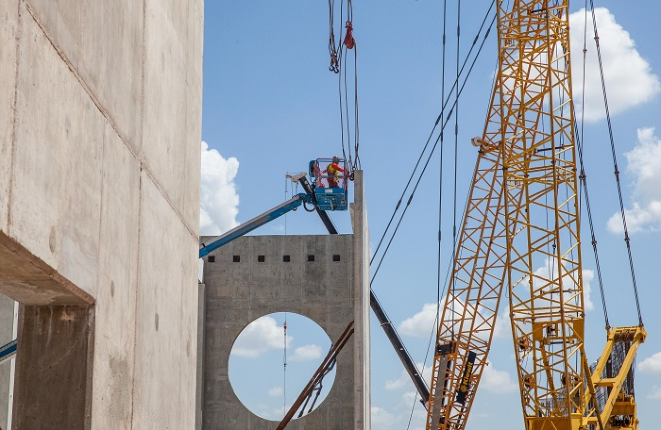 A worker 40 feet in the air secures the top of a precast concrete panel at the Salt Reduction Building (SRB), part of the Waste Isolation Pilot Plant’s Safety Significant Confinement Ventilation System. The large hole in the corner support wall is where prefiltered air from the SRB will move on to the system’s high-efficiency particulate air (HEPA) filters in the New Filter Building.