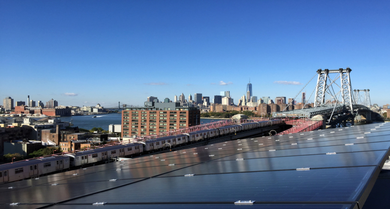 Photo of a solar array overlooking a city with train, bridges, and buildings