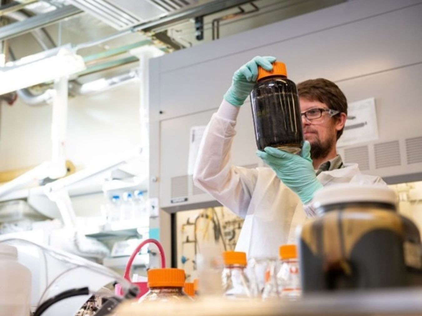 a photo of a person looking at a jar in a lab.