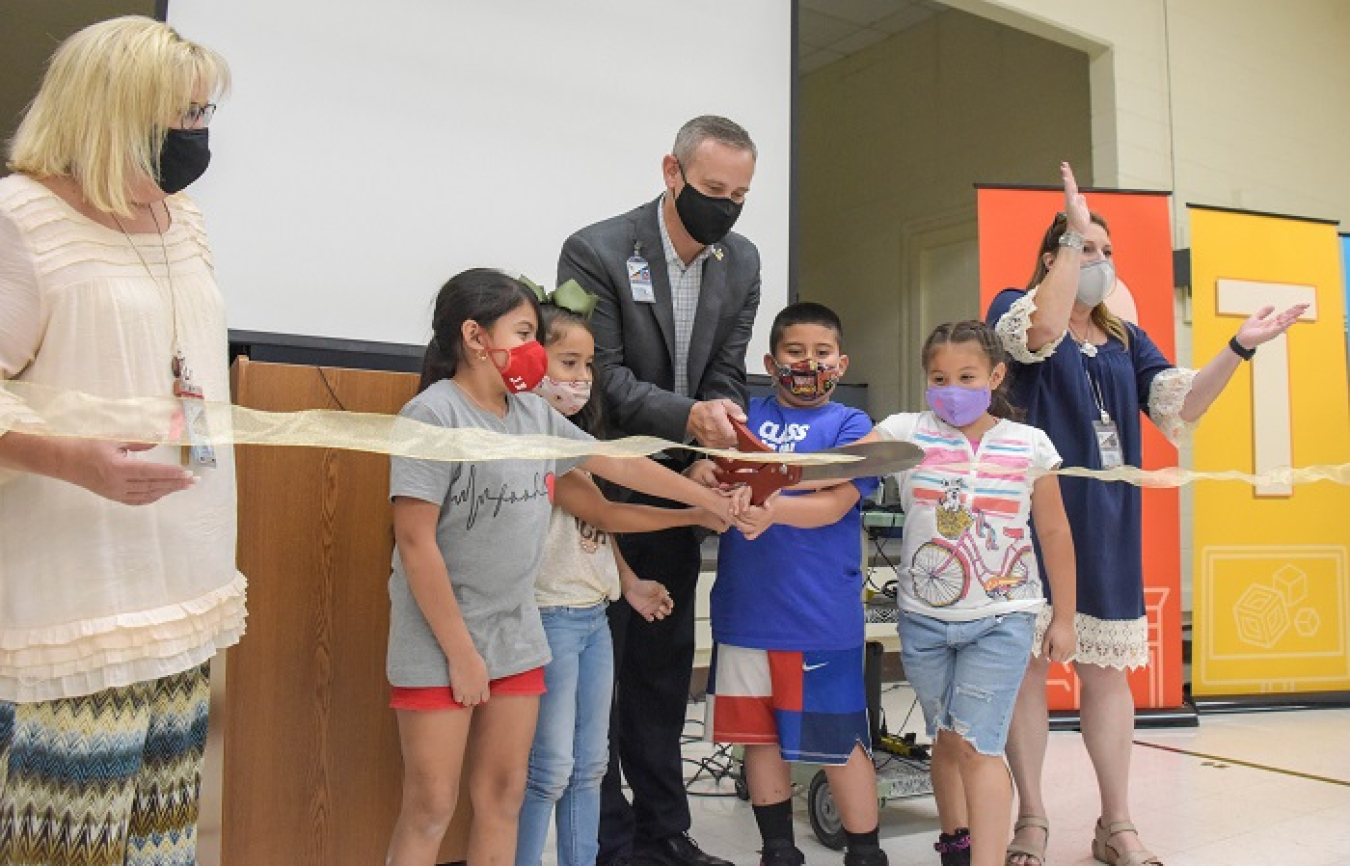 Hobbs Municipal Schools Superintendent Gene Strickland, center, with Sanger Elementary Principal Kelly Inman, far left, and Jefferson Elementary Principal Pam Randall, far right, join students to cut the ribbon on a new Cal Ripken, Sr. Foundation STEM Center mobile laboratory at Jefferson Elementary.