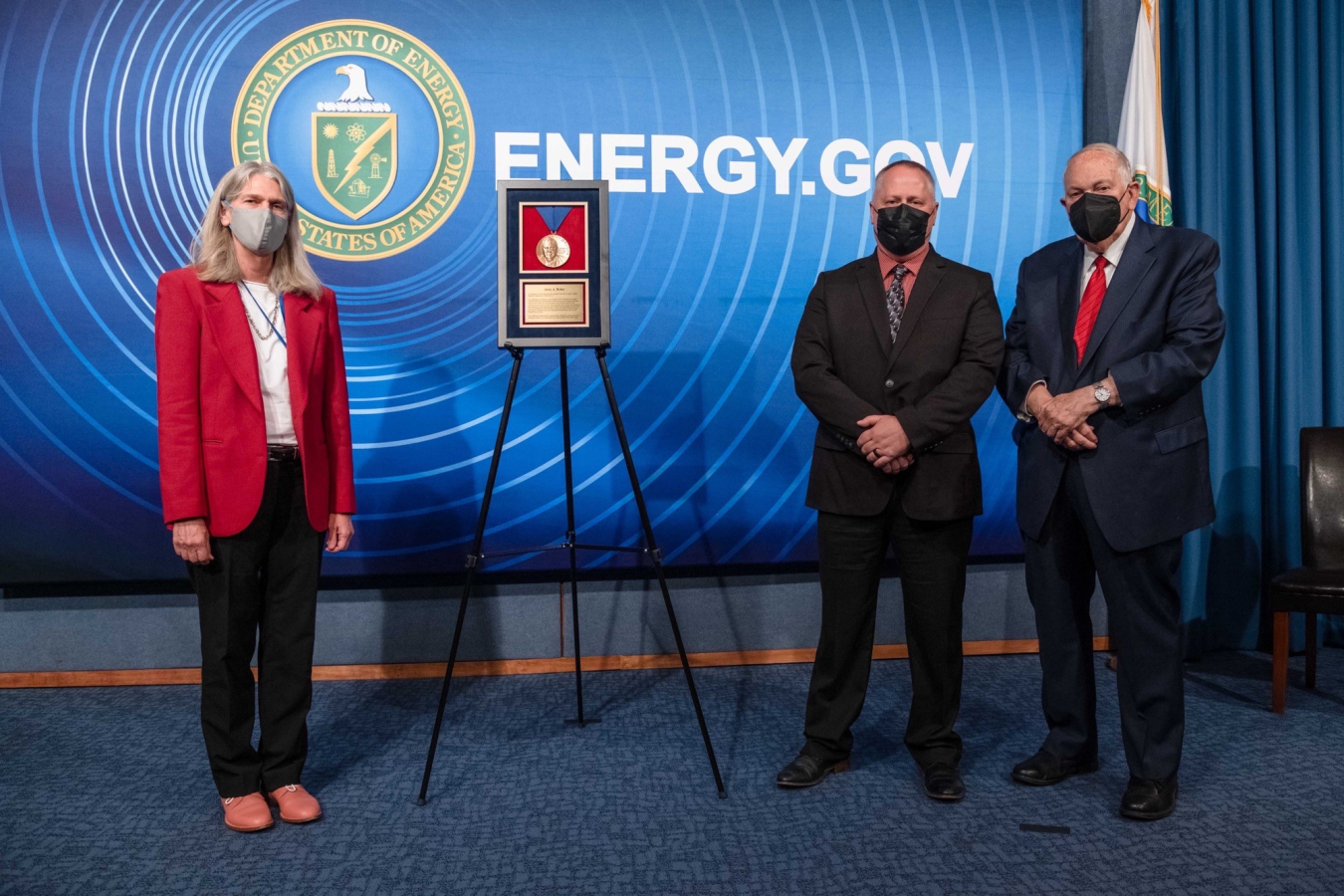 Administrator Jill Hruby, Jerry Weber, and Ambassador Linton Brooks stand next to the Linton F. Brooks Medal for Dedication to Public Service.