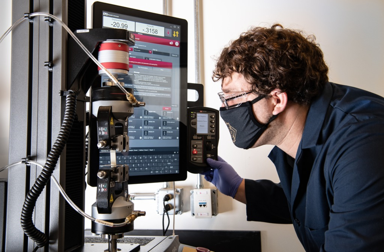 A Photo of a person in a lab, next to a computer monitor and lab equipment. 