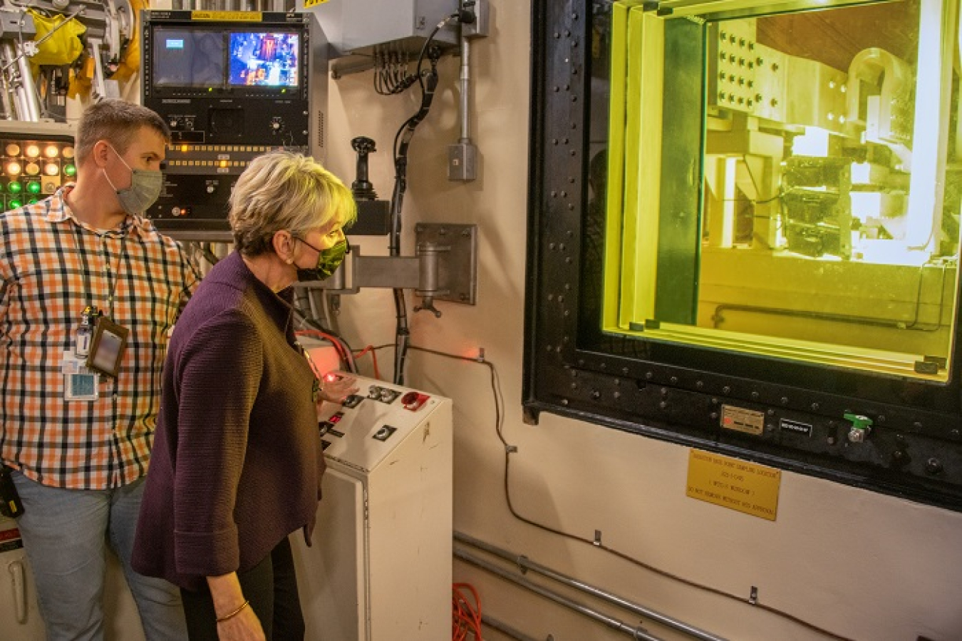 Energy Secretary Jennifer Granholm pushes the button to weld a cannister in the Defense Waste Processing Facility as Matt Still, senior production operator, gives instruction.