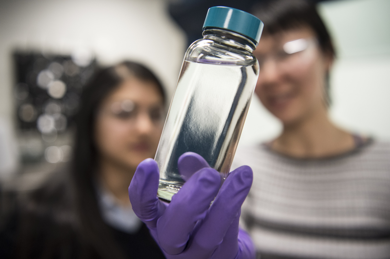 NREL researchers examine a container containing a “drop-in” biofuel synthesized at NREL. Image courtesy of Dennis Schroeder