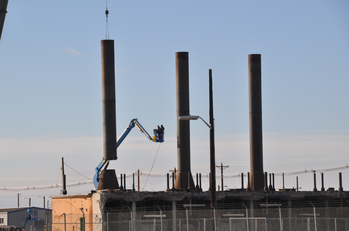 A crane lifts the first of three old ventilation stacks after workers cut through it. Removal of the 50-foot-tall towers changes the Hanford Site skyline near the Columbia River.