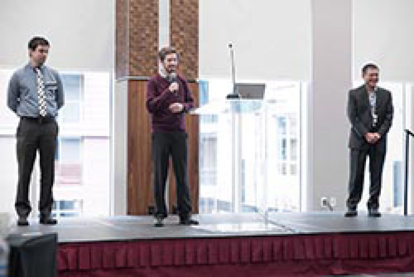 Three men presenting on stage.