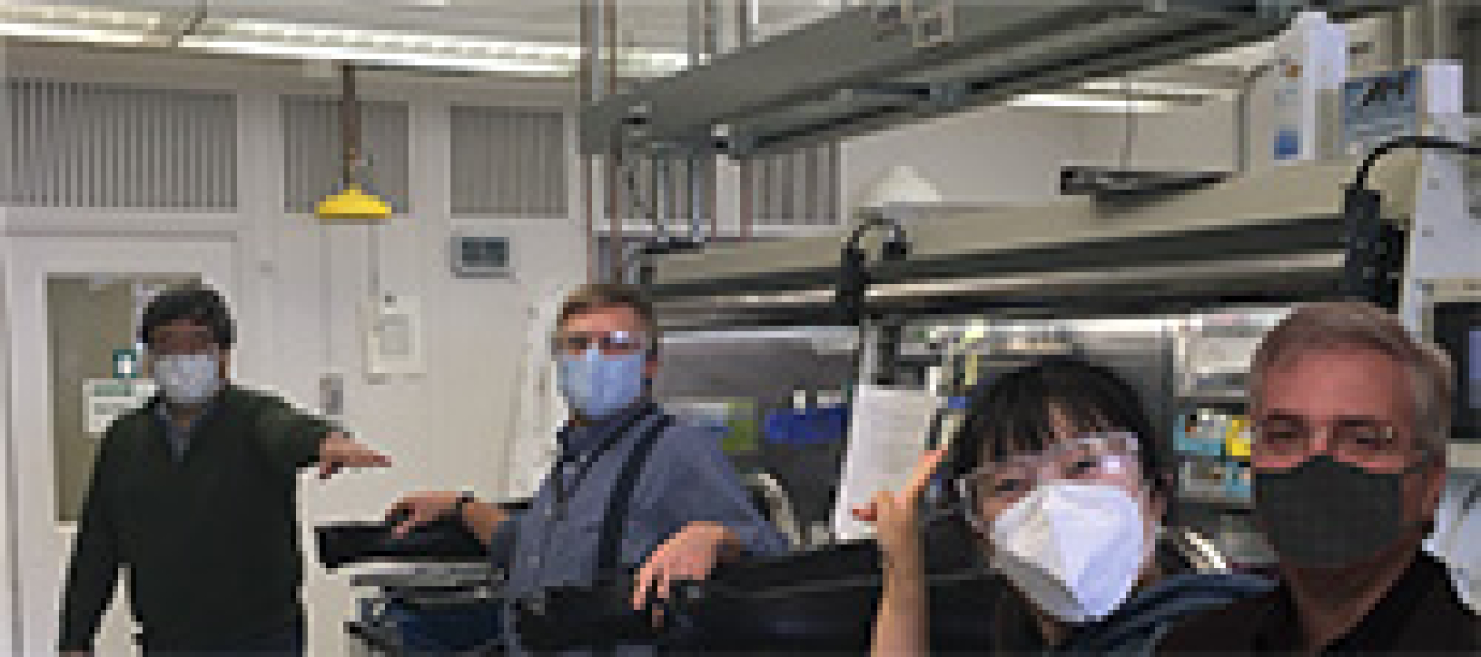 Four people wearing masks in a lab.