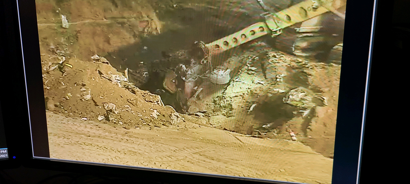 An extended-arm excavator retrieves the final waste from the Accelerated Retrieval Project IX facility on Dec. 6, 2021. The final waste retrieval is pictured on a computer monitor inside a control room at the DOE Idaho National Laboratory Site.