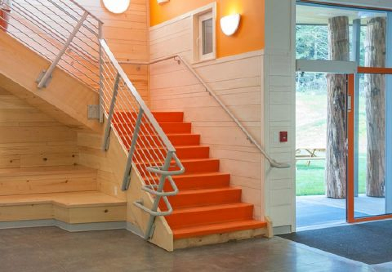 A staircase and corridor of a school, with the glass doors of the building entrance.