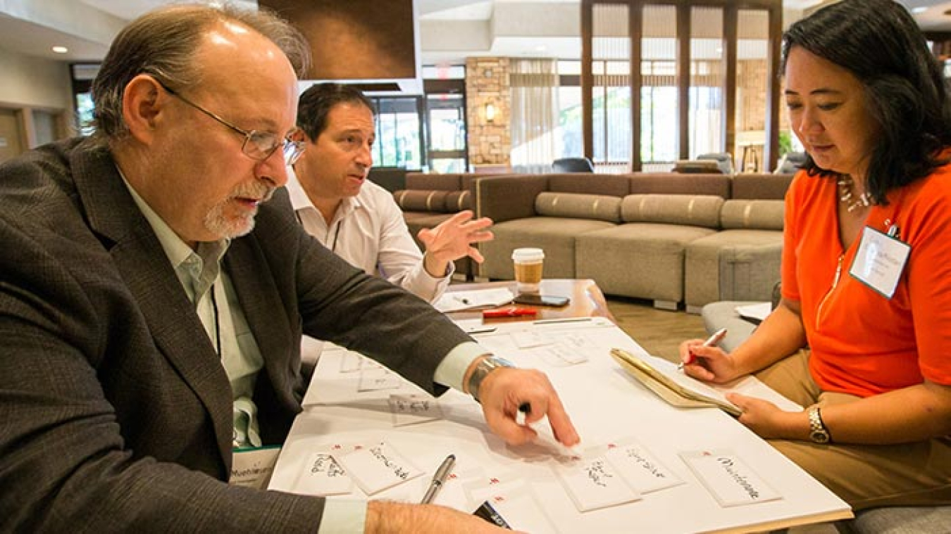 Image of three people, two males and a female, working together at a table.