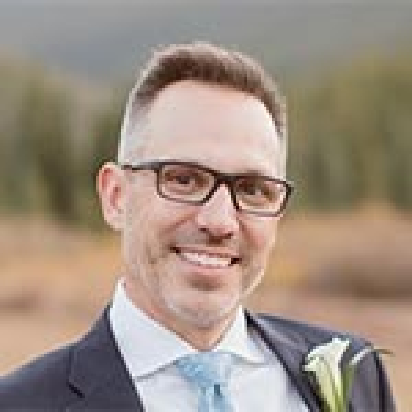 Image of a man wearing a suit, tie, and a flower on his lapel