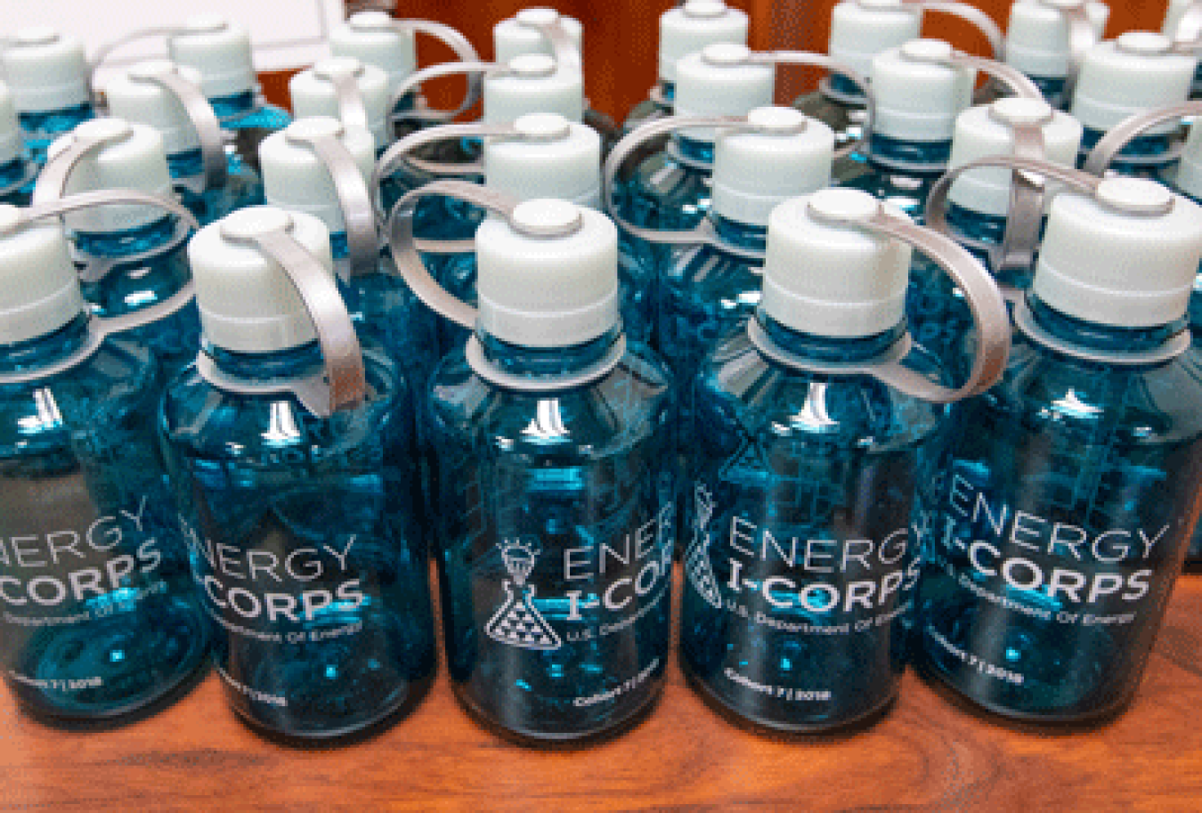 A line of water bottles with the Energy I-Corps logo on their sides