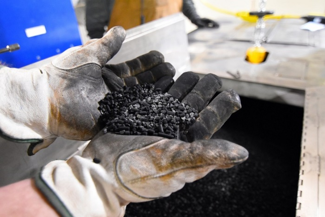 A crew member at the Hanford Site's Waste Treatment and Immobilization Plant holds a handful of small carbon pellets loaded into the emissions treatment system in the Low-Activity Waste Facility.