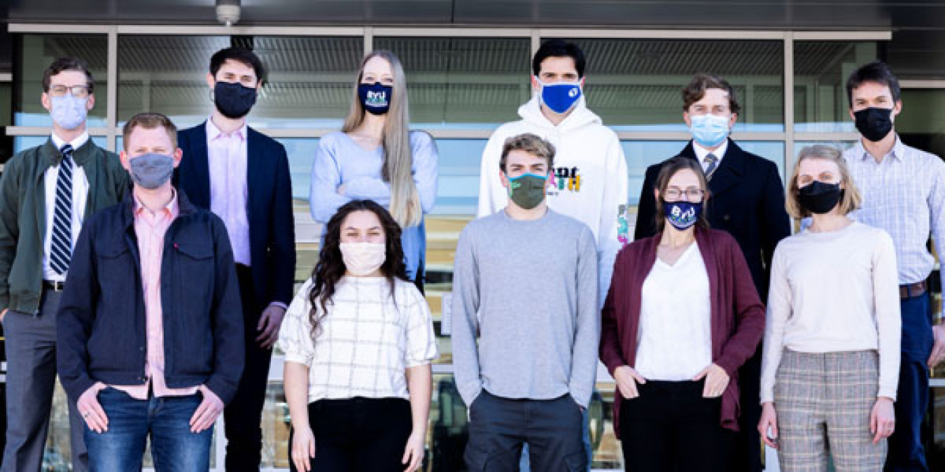 Students in masks standing in two rows on tiered bleachers.