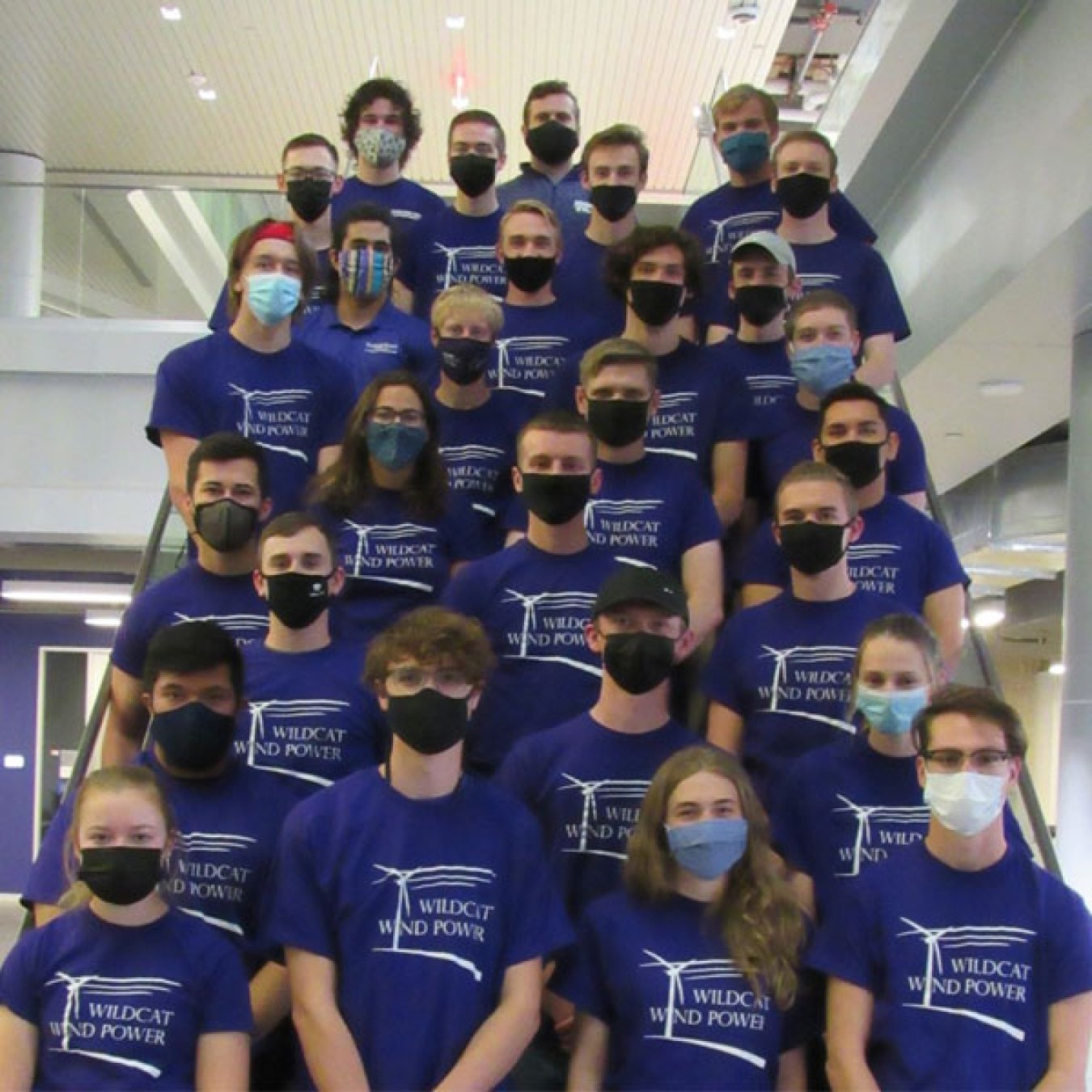 Students wearing face masks and matching “Wildcat Wind Power” t-shirts standing on a staircase.