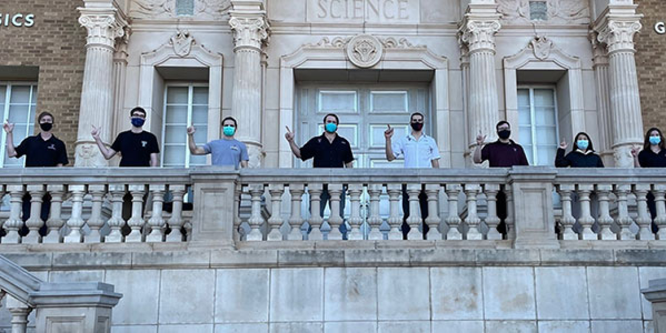 A row of students in Texas Tech University apparel in front of a mural of wind turbines.