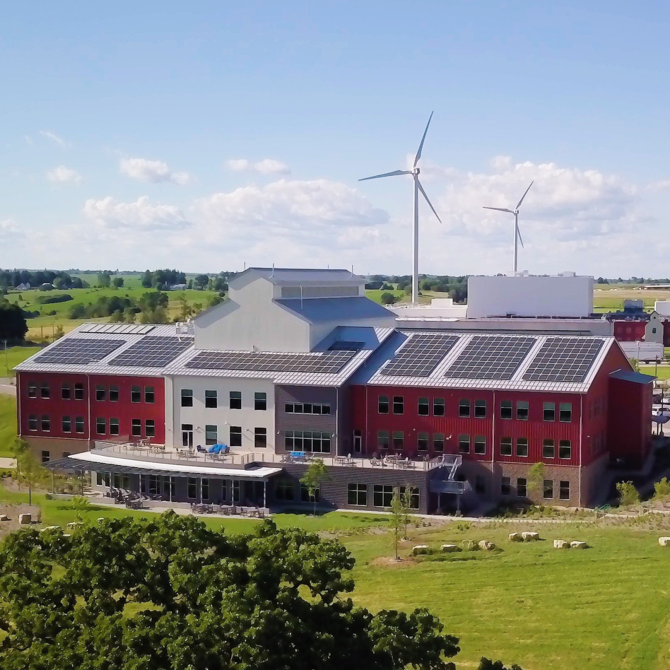 Red school with solar panels in front of a wind turbine.