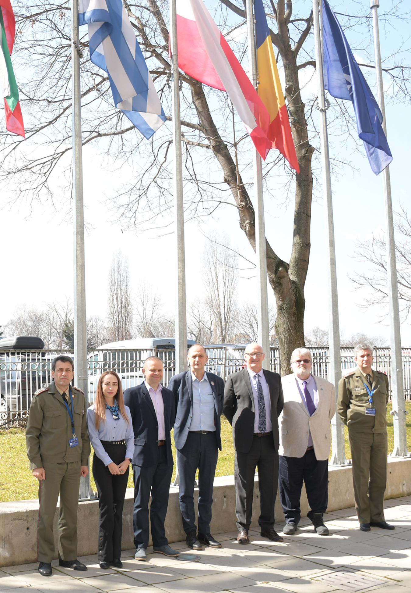 Participants in the joint meeting line up outside under several countries' flags