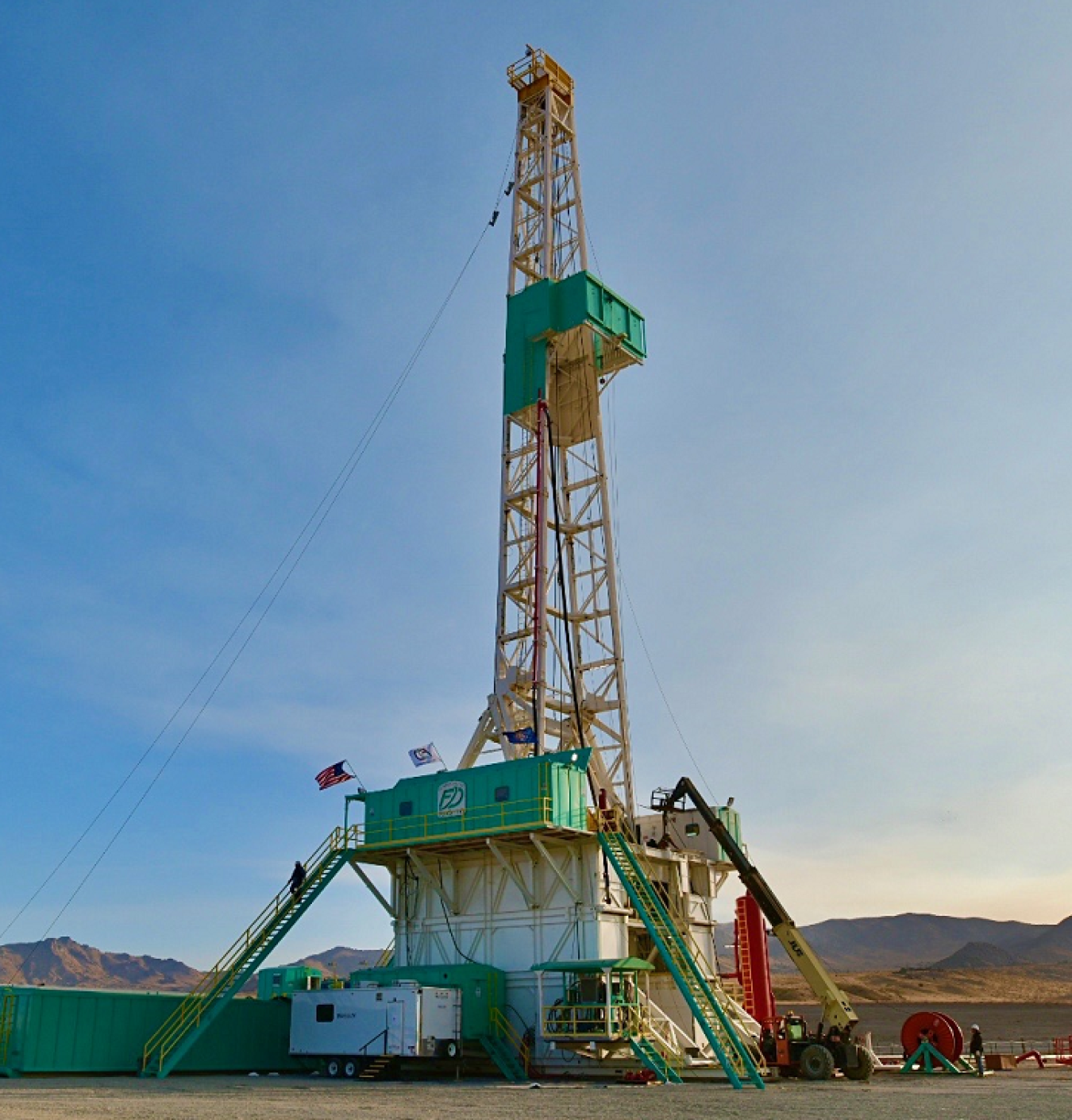 Geothermal well erected into the sky in desert-area surrounding by mountains.