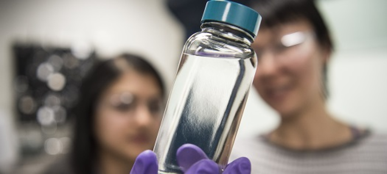 scientists pose with a clear vial containing a low-carbon biofuel.