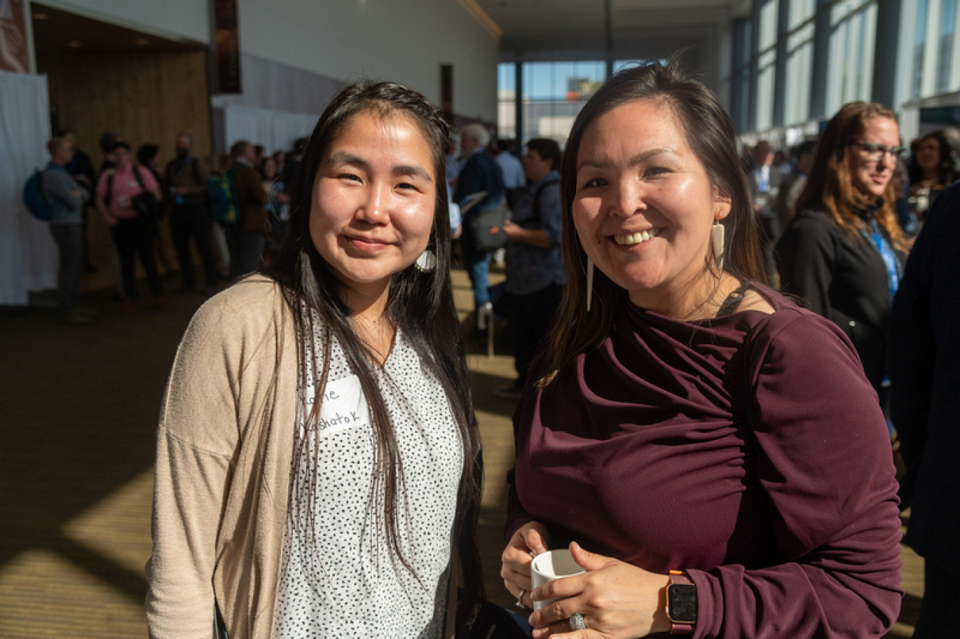 Two ArcticX participants stand together in the booth area. 