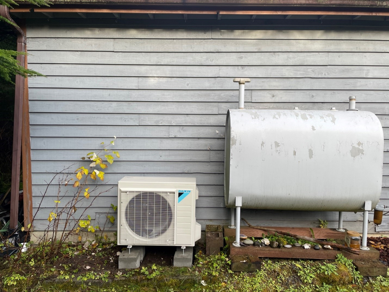 An oil tank and cooling unit on the outside of a house.