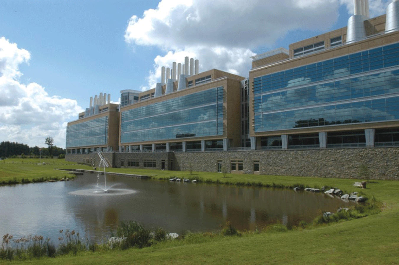 Three large buildings in a row next to a pond.