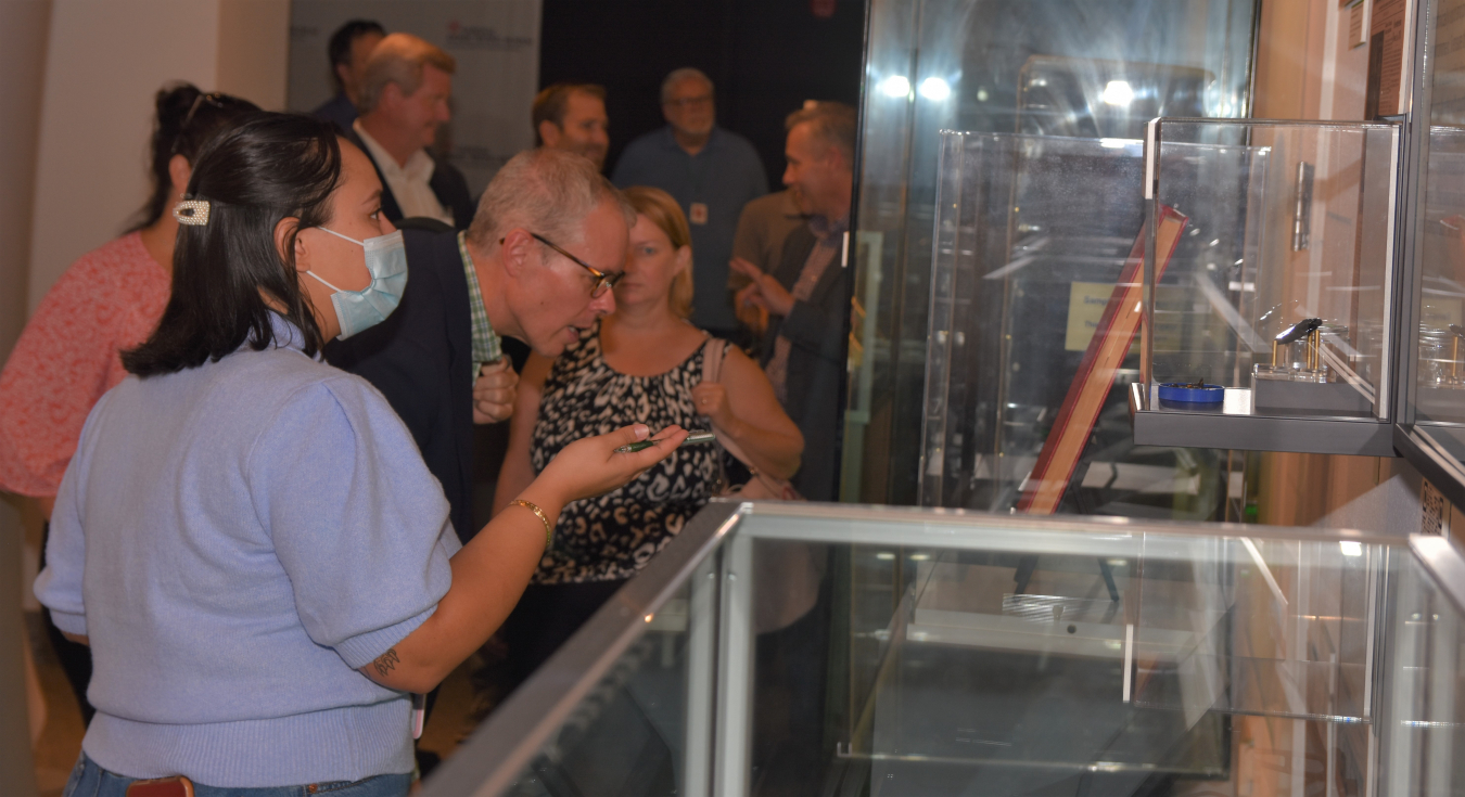 EM Senior Advisor William “Ike” White takes a close look at a book on display from the Hanford Site in a new EM exhibit at the National Atomic Testing Museum in Las Vegas. At left is Parker Arecchi, the museum’s curator.