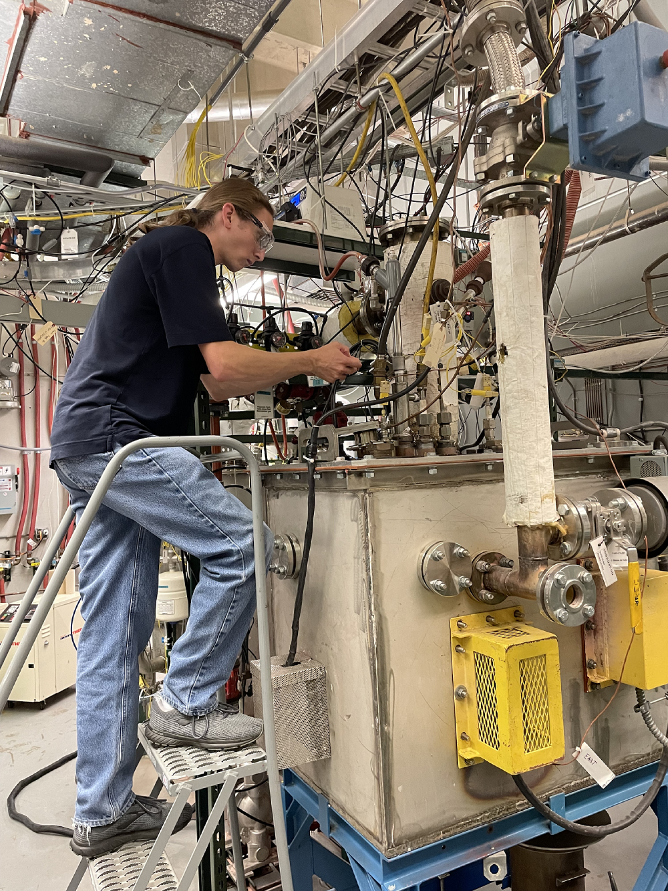 Miles Johnson, a shift engineer at the Waste Treatment and Immobilization Plant at the Hanford Site, observes a molten glass pool inside a prototype melter at the Vitreous State Laboratory at The Catholic University of America in Washington, D.C.