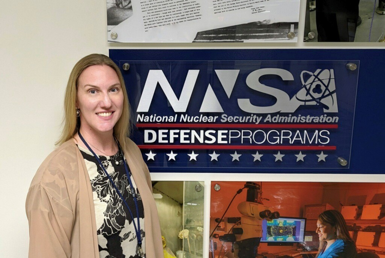 Dr. Nelson standing in front of the Office of Defense Programs collage at NNSA headquarters.