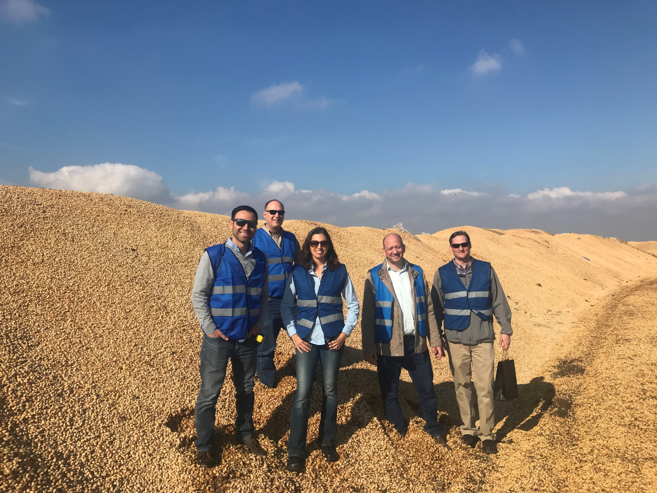 5 people with blue vests standing on a hill