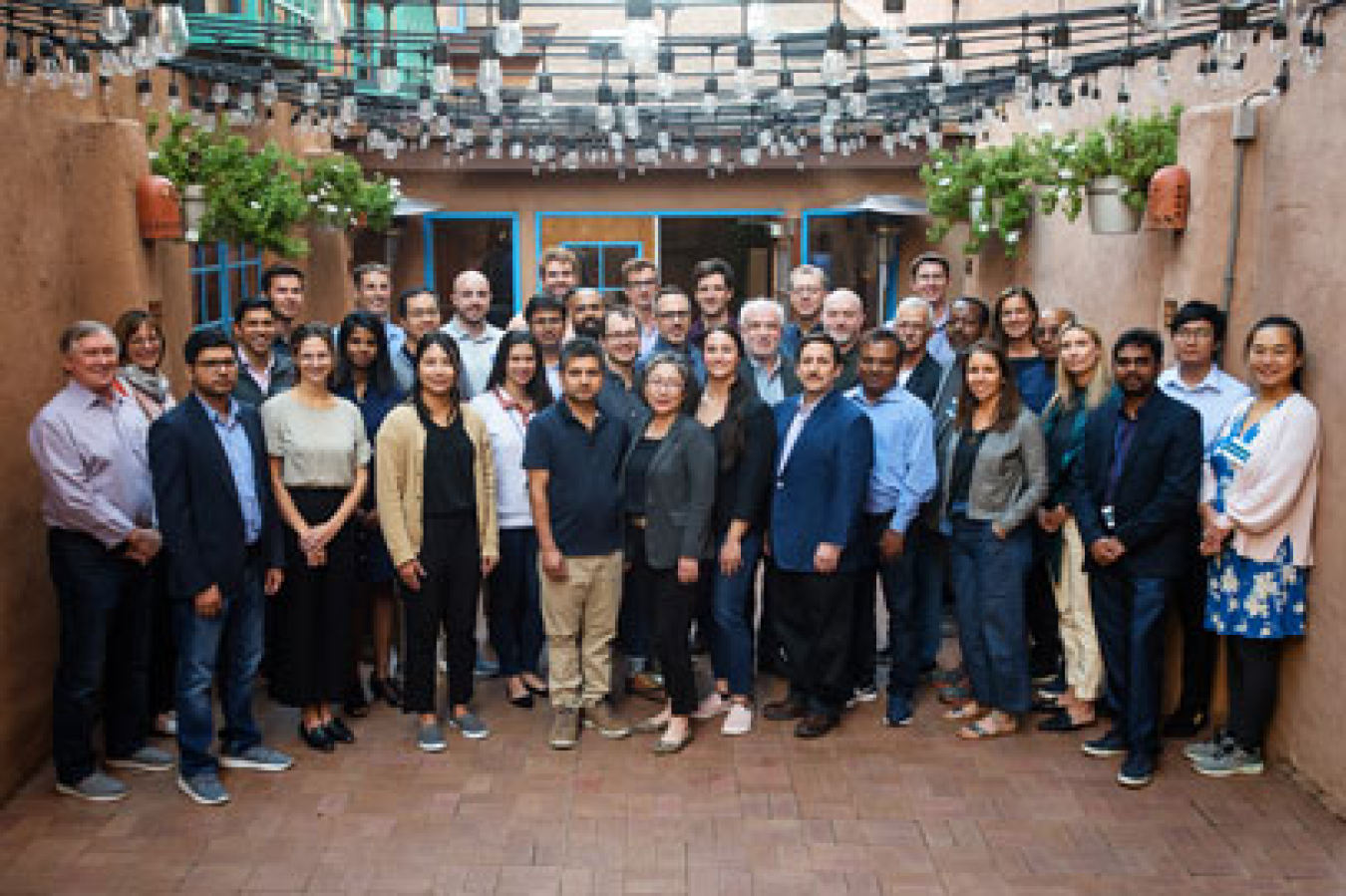 Men and women stand together for a group photo on an enclosed outdoor patio.