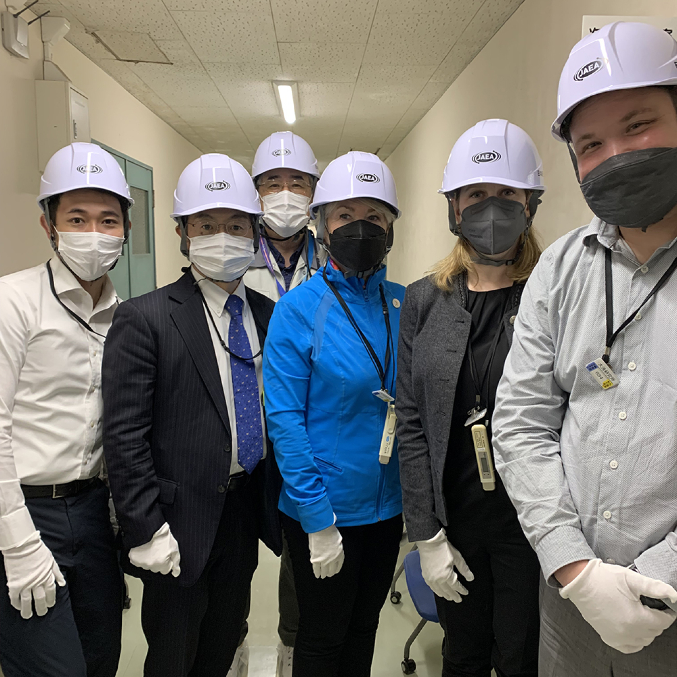 A group of people in protective gear pose for a photo in a hallfway.