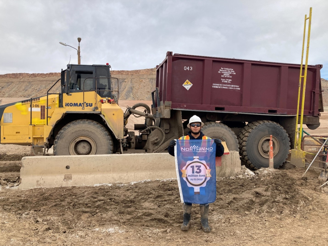 This sealed steel container of uranium mill tailings brought the Moab Uranium Mill Tailings Remedial Action Project's cumulative total to 13 million tons of the material removed from the Moab Site for disposal at the Crescent Junction, Utah, disposal cell. Moab Project Laborer Alfredo Tellez is pictured holding a banner marking the achievement. 