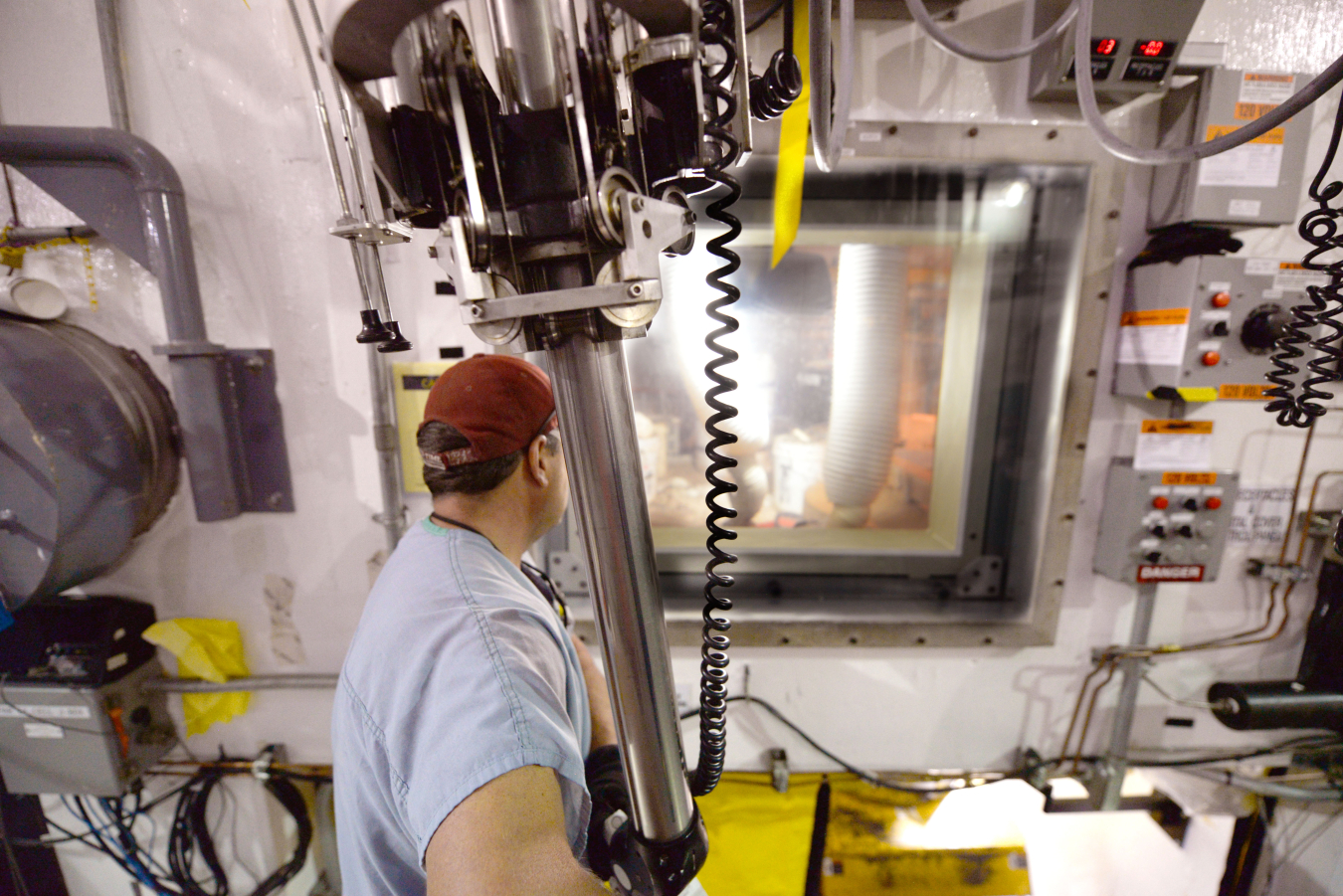 An operator at the Transuranic Waste Processing Center sorts waste using manipulators in a heavily shielded room known as a hot cell. Higher level radioactive waste called remoted-handled transuranic waste requires use of the special equipment to provide distance and shielding from the material. 