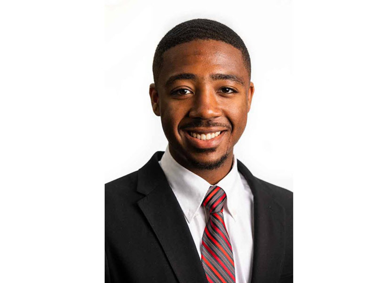 Headshot of young man in black suit with white collared shirt and red and grey striped tie.