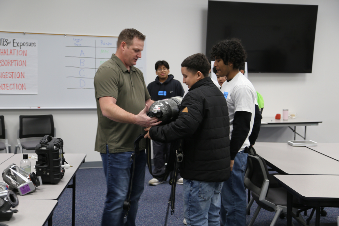 Hanford Mission Integration Solutions employee Scott Downing, left, shows high school students some of the respiratory equipment used at Hanford and other EM sites to ensure worker safety. 