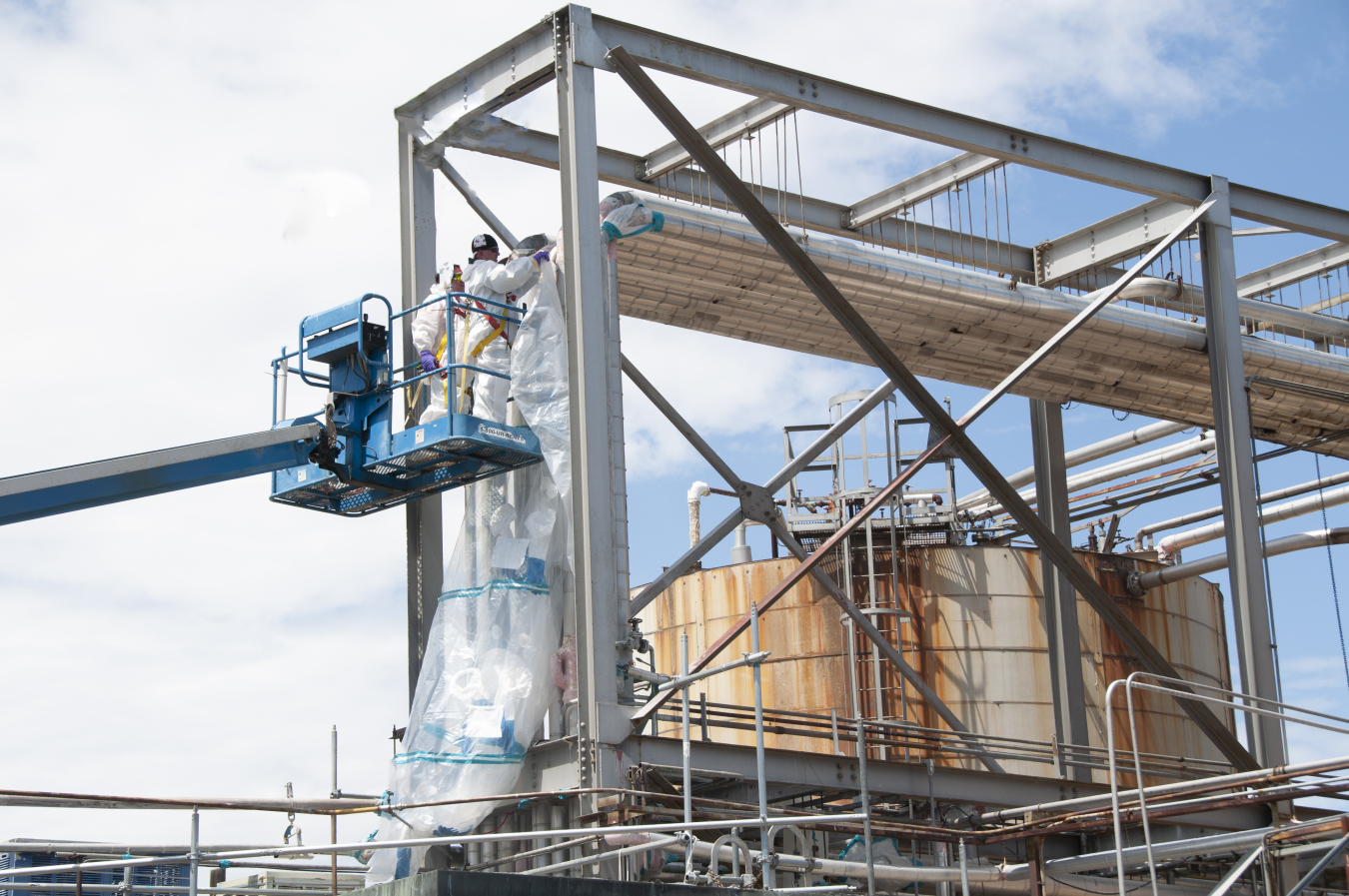 Crews at the Plutonium Uranium Extraction Plant install bags on a piping system to safely remove asbestos-containing material in the 203-A Acid Storage Area.