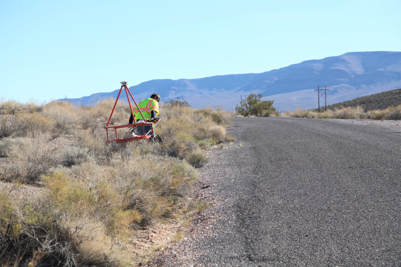 Geophysicist Jeff Warren pulls an electromagnetic metal detector with a mounted GPS on top.