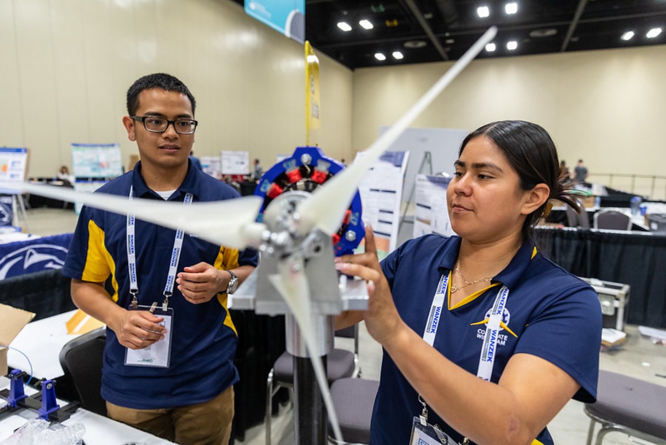 Two participants in the Collegiate Wind Competition adjust their wind turbine model.