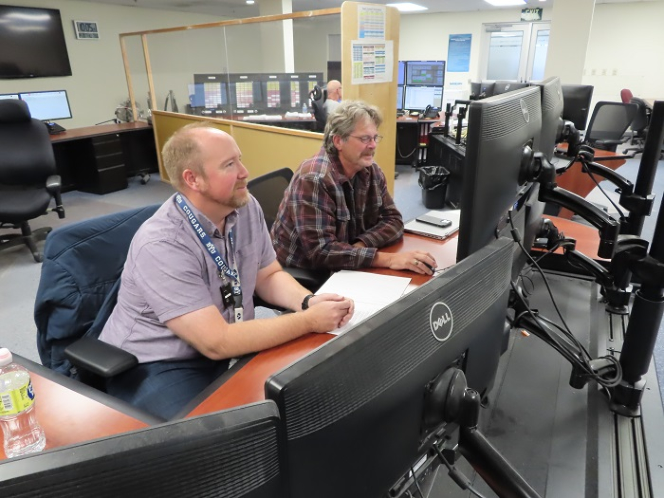 Nolan Wright, Washington River Protection Solutions Instrumentation and Controls engineer, left, and Darin Wood, nuclear chemical operator, talk with operators at the Waste Treatment and Immobilization Plant control room to test the transfer line communication system between the plant and Hanford’s AP Tank Farm.