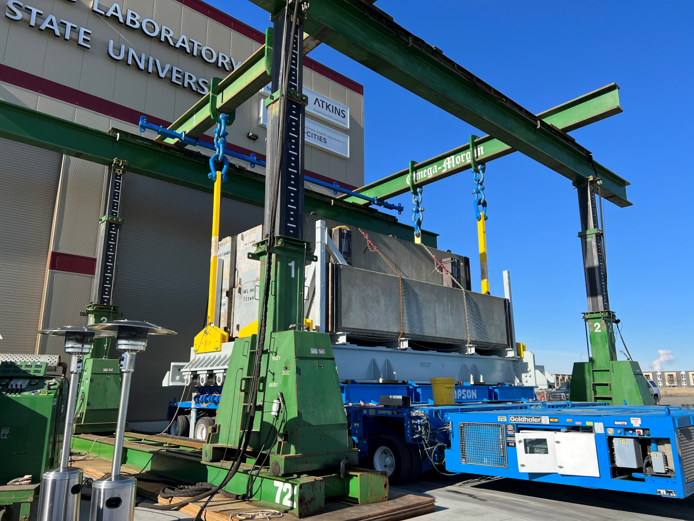 Concrete blocks are loaded onto a metal base and transporter during tests on a gantry crane system that will lift replacement melters for the Waste Treatment and Immobilization Plant at the Hanford Site.