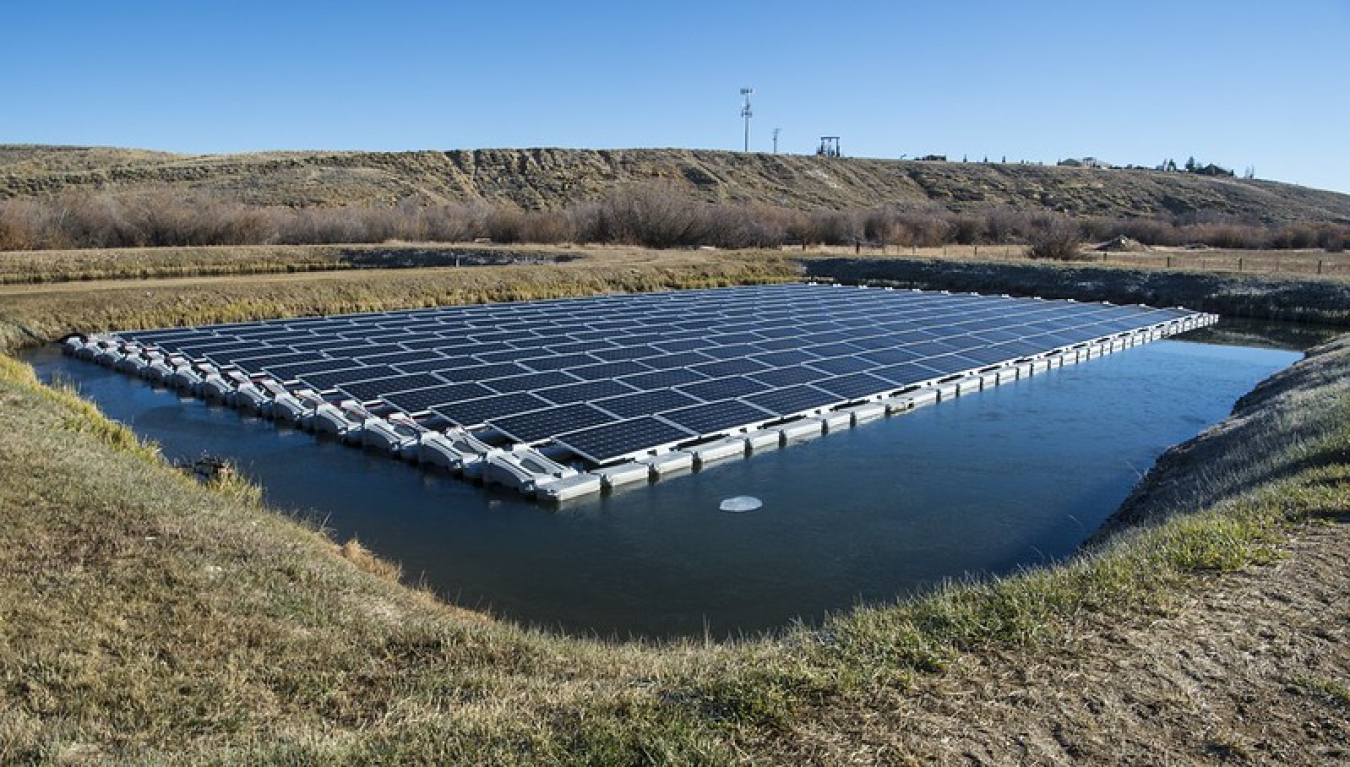 Rows of solar panels on top of a water retention pond in a water resource recovery facility on a sunny day