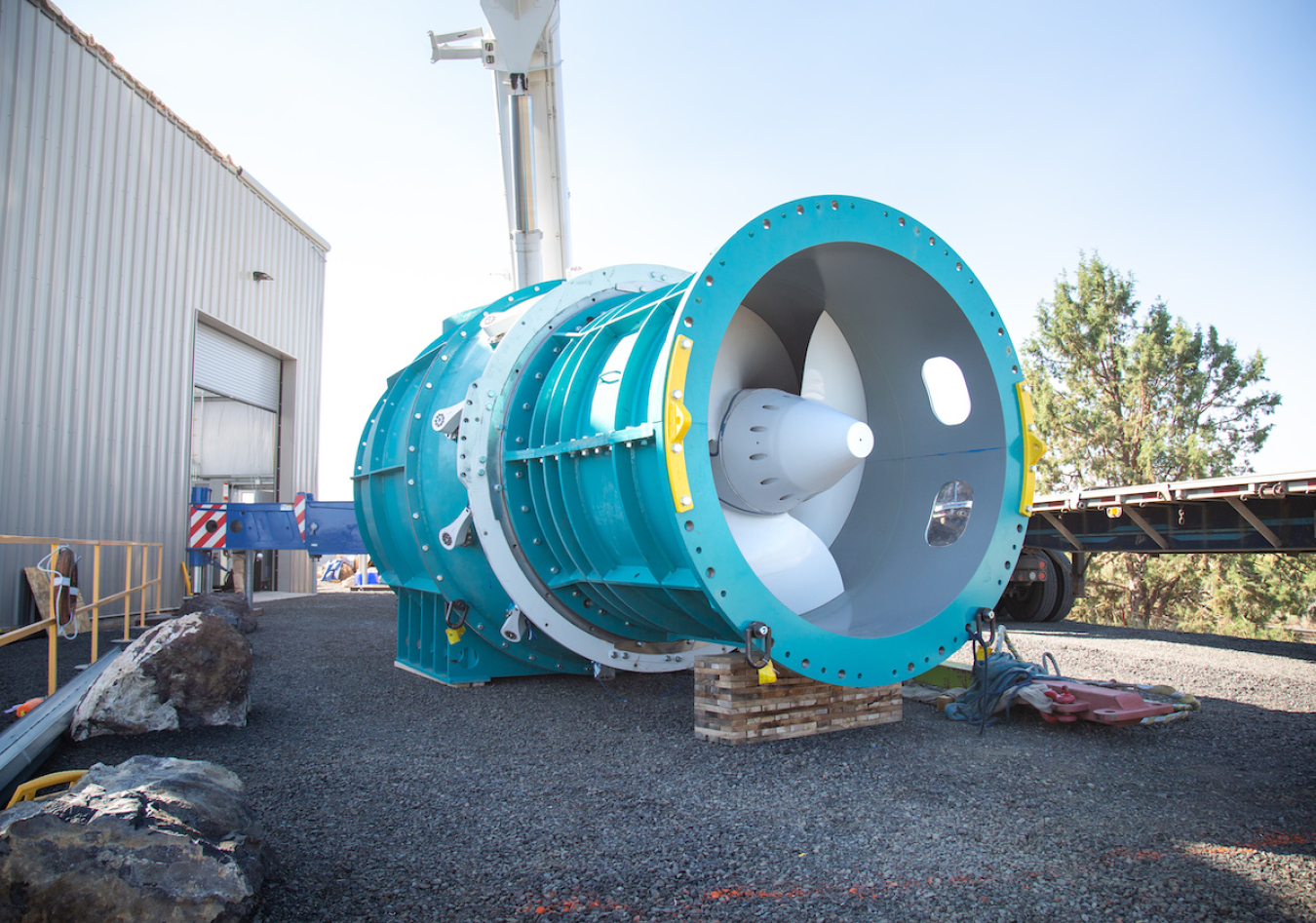 A large blue and white turbine is shown outside a warehouse building