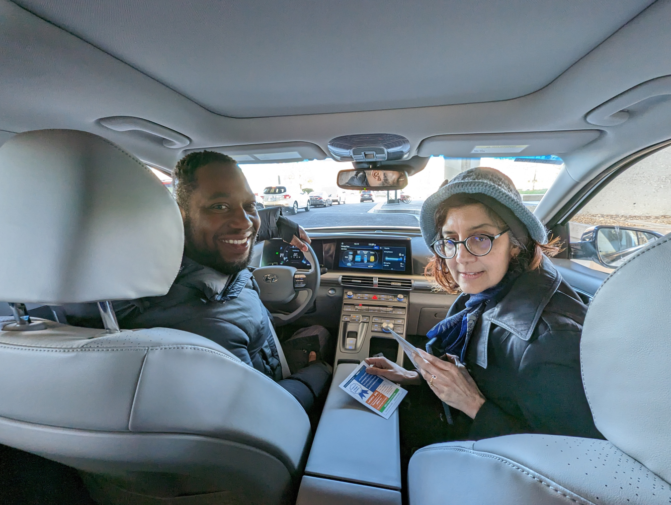 An inside look at the fuel cell car. Two individuals are sitting in the front seat and looking back at the camera. 