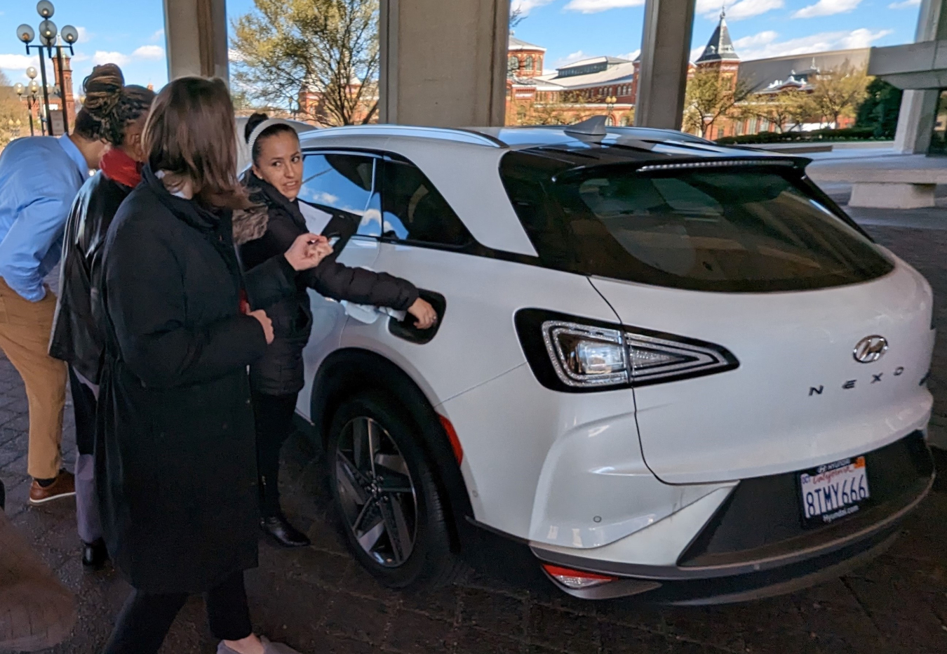 A woman gestures to a white car.