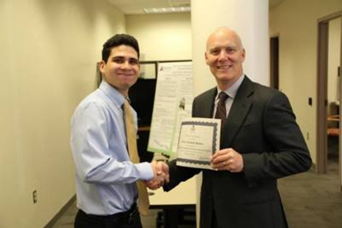 Pierre Almeda receiving his SULI certification from Ames Laboratory director Adam Schwartz