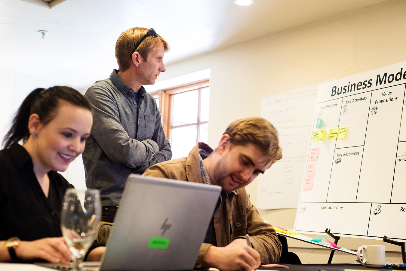 Three people work near a laptop and poster board.