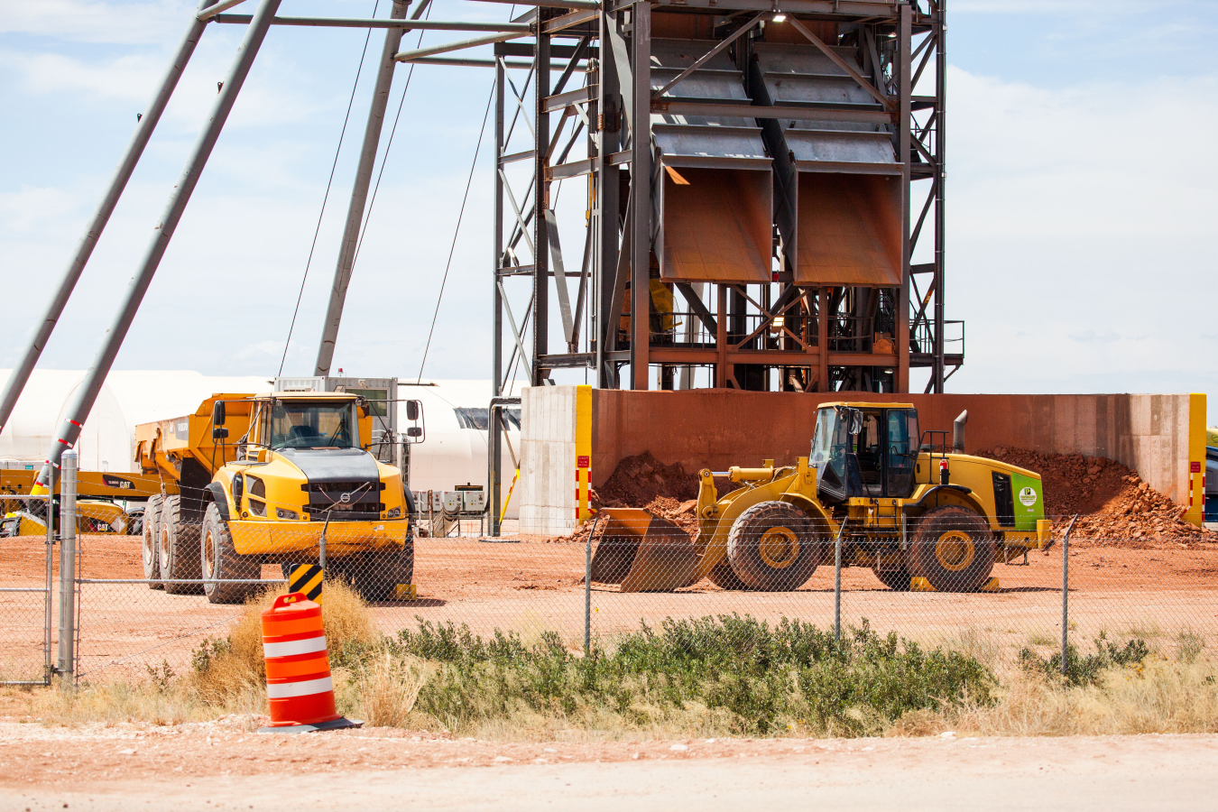 Debris from shaft-sinking activities is loaded into a dump truck at EM’s Waste Isolation Pilot Plant. The chutes shown in the background carry debris out of the utility shaft being constructed and dumps it on a concrete pad where it’s scooped up by a front-end loader.